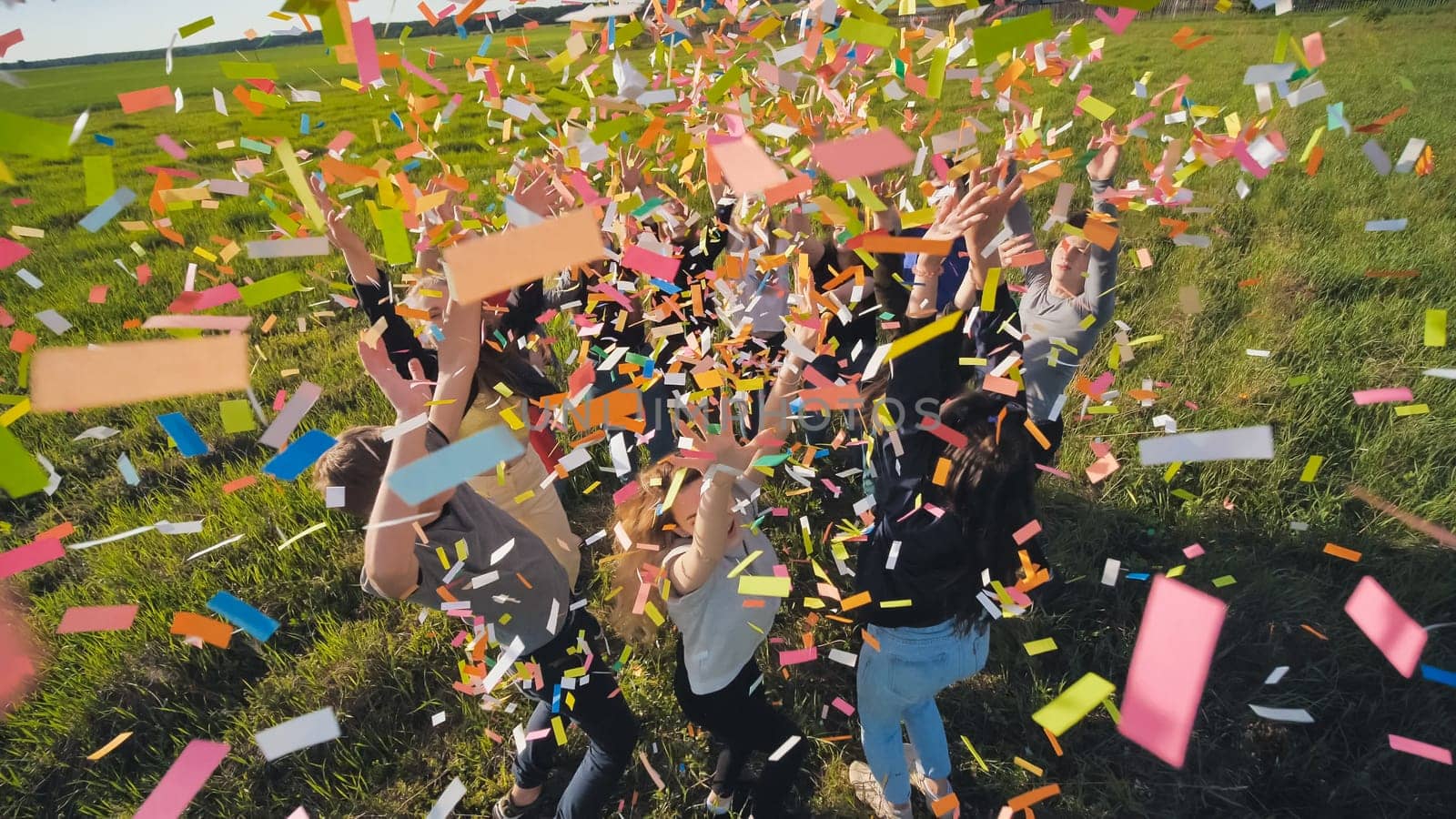 A group of friendly friends toss up candy at sunset in a field