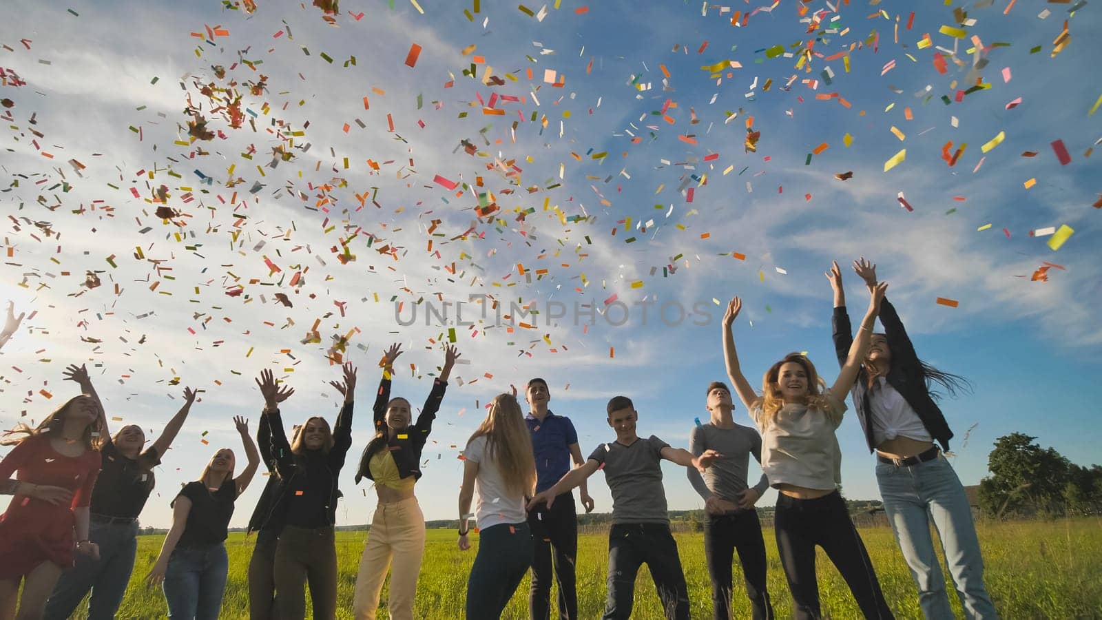 A group of friendly friends toss up candy at sunset in a field