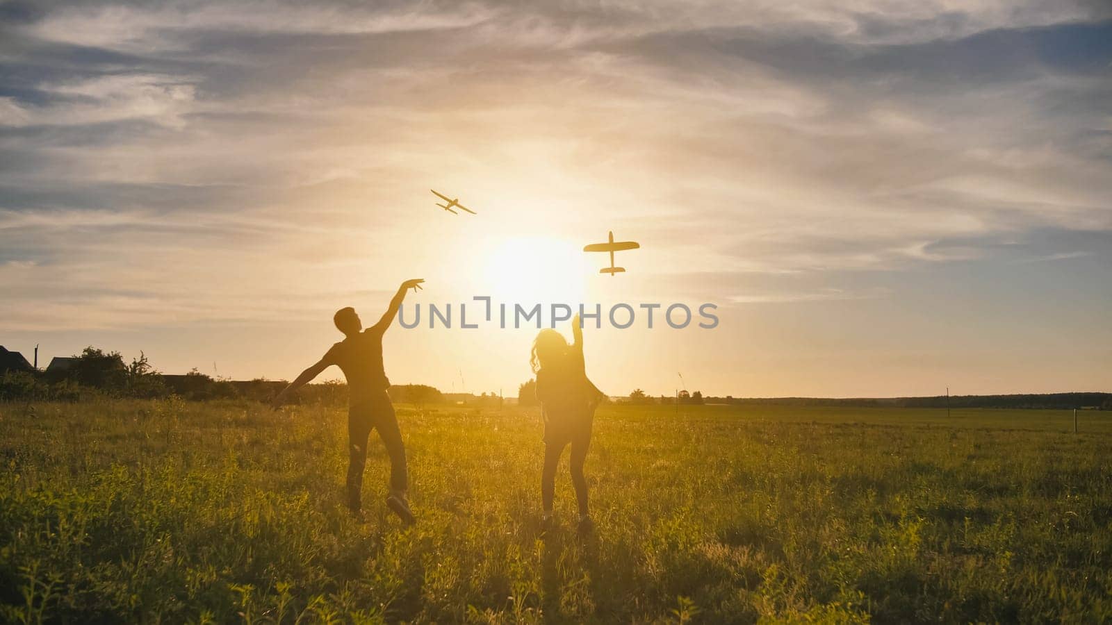 A guy and a girl launch a paralon plane at sunset