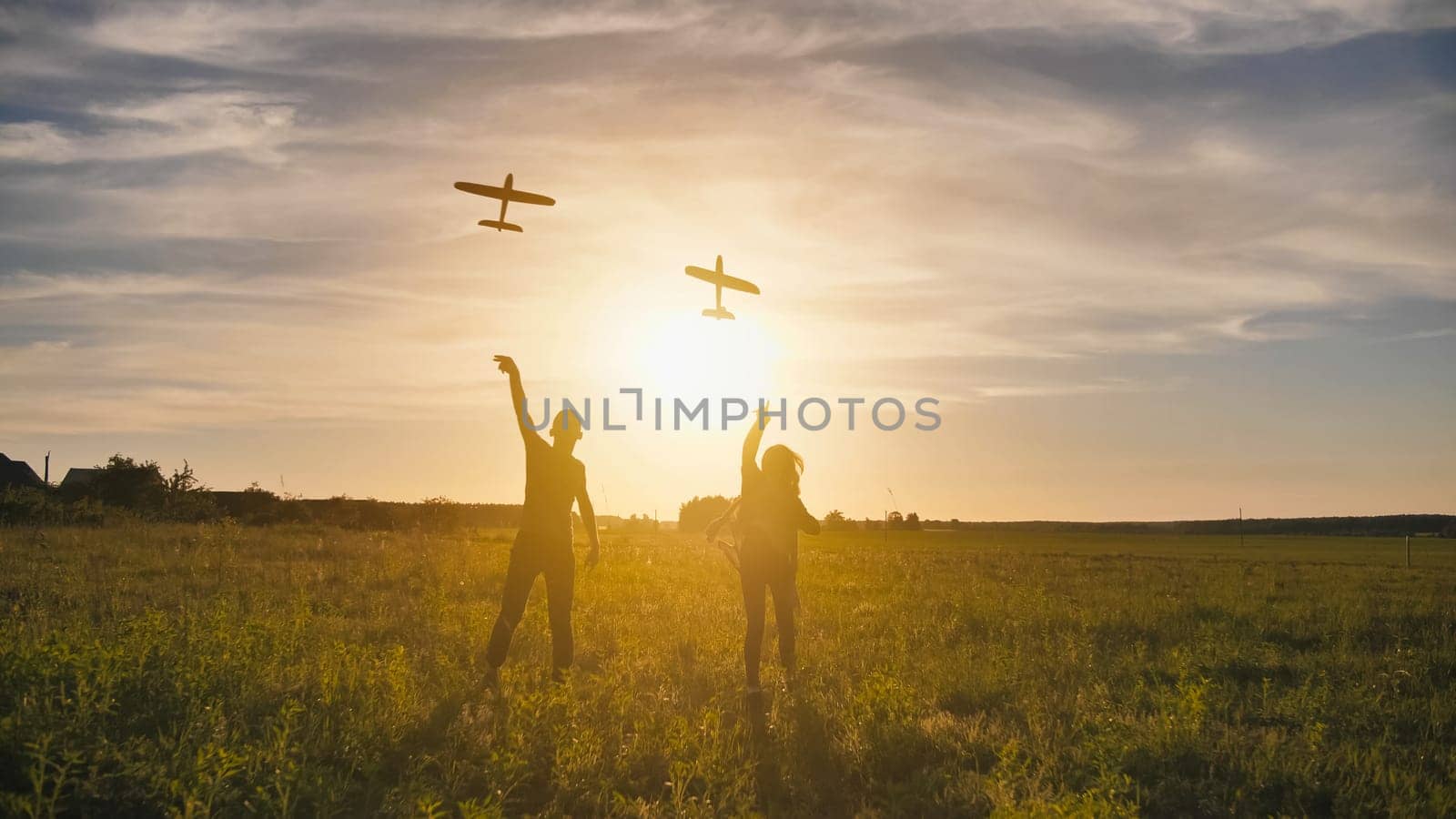 A guy and a girl launch a paralon plane at sunset