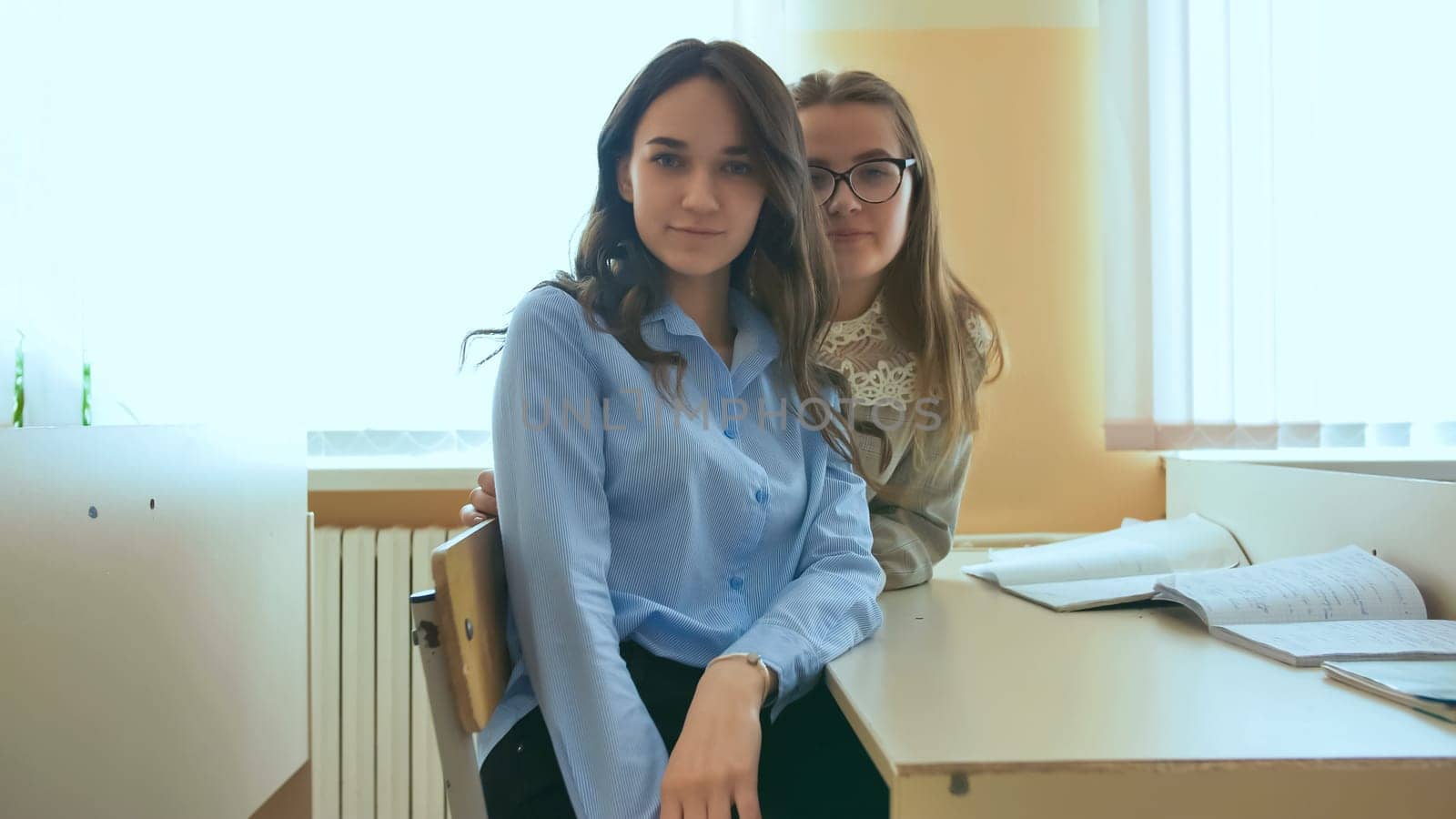 Two schoolgirls are smiling between lessons at their school