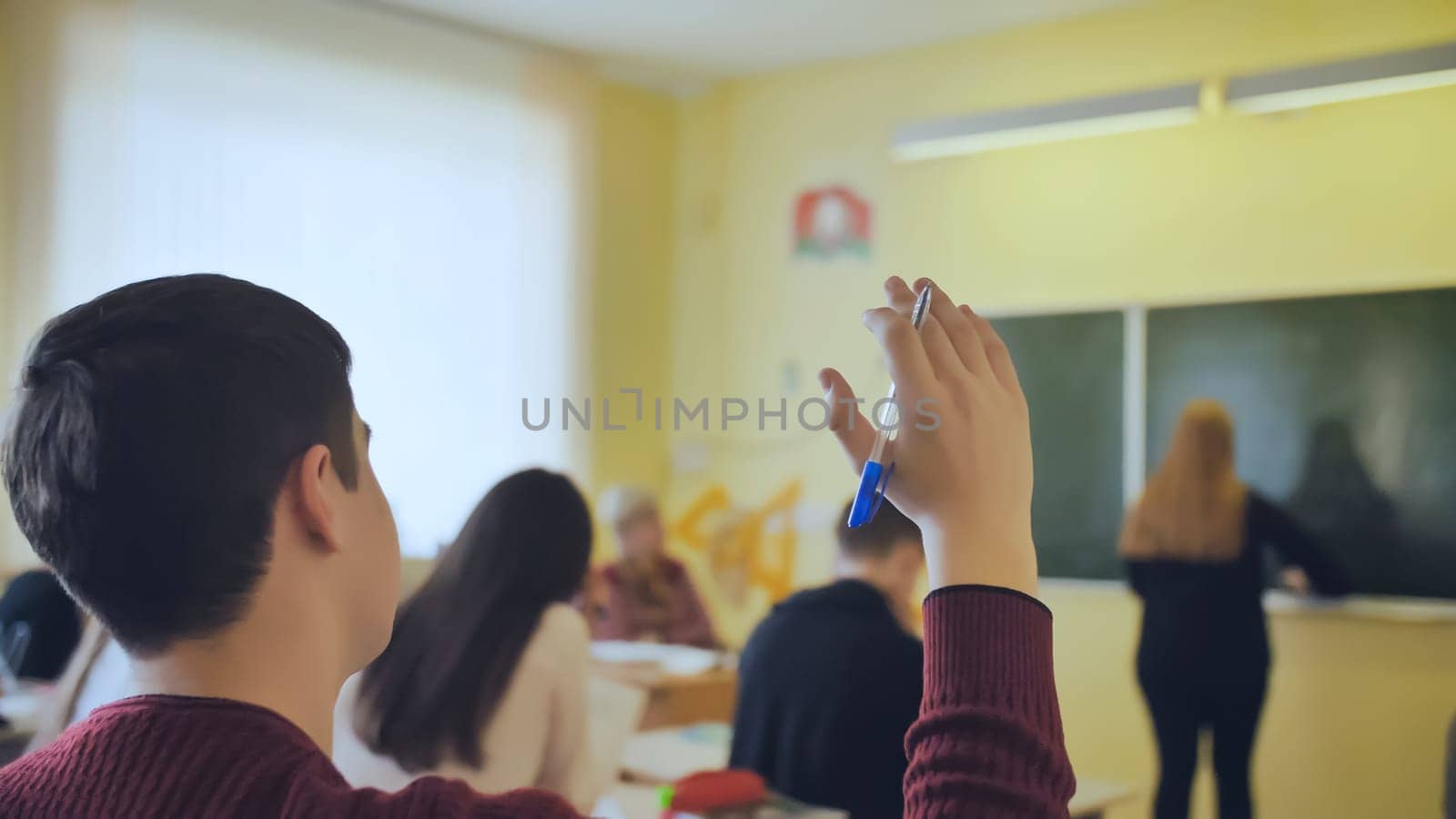 High school student raises his hand during the lesson