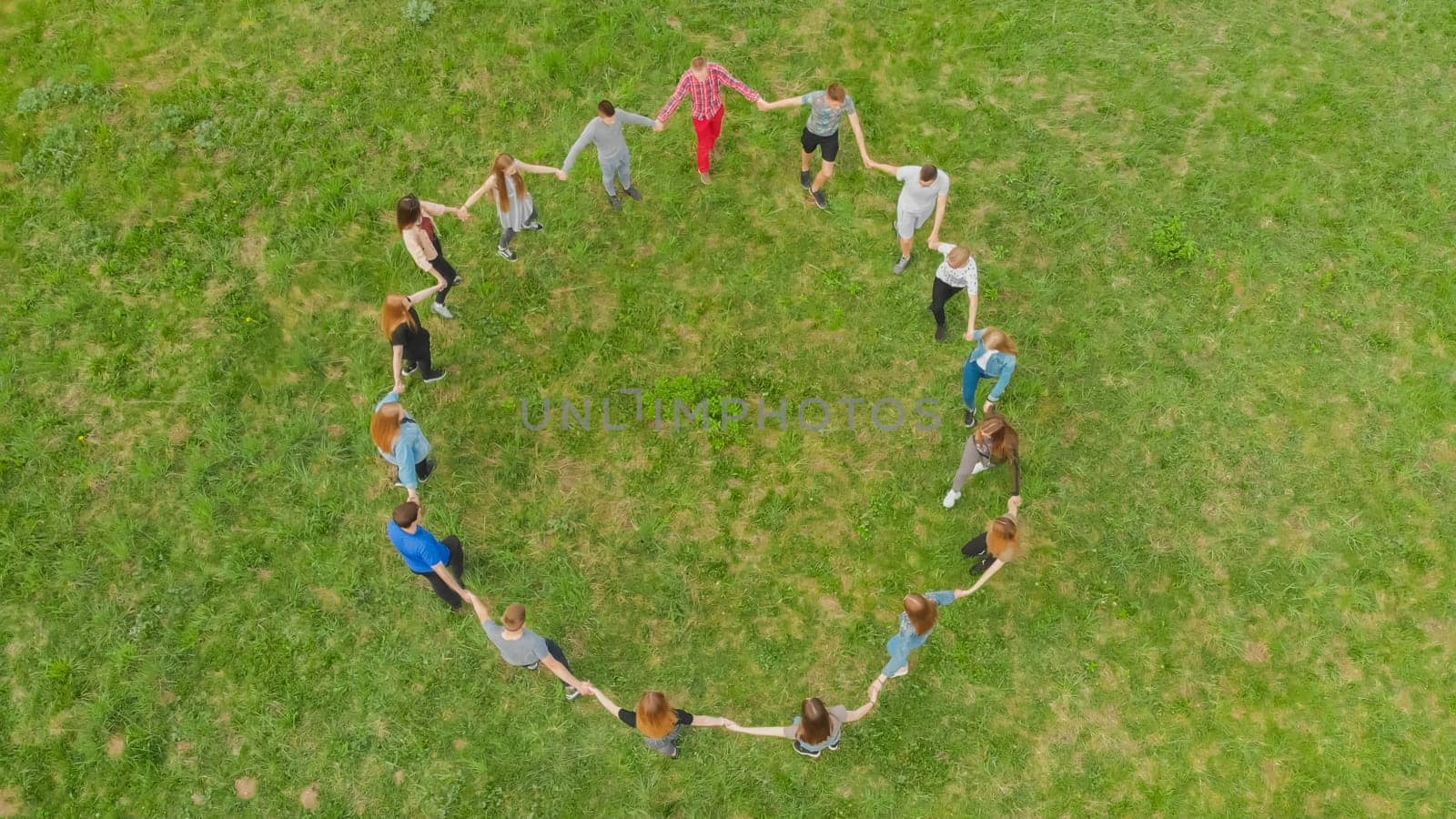 Friends in a circle holding hands make a round dance in the field