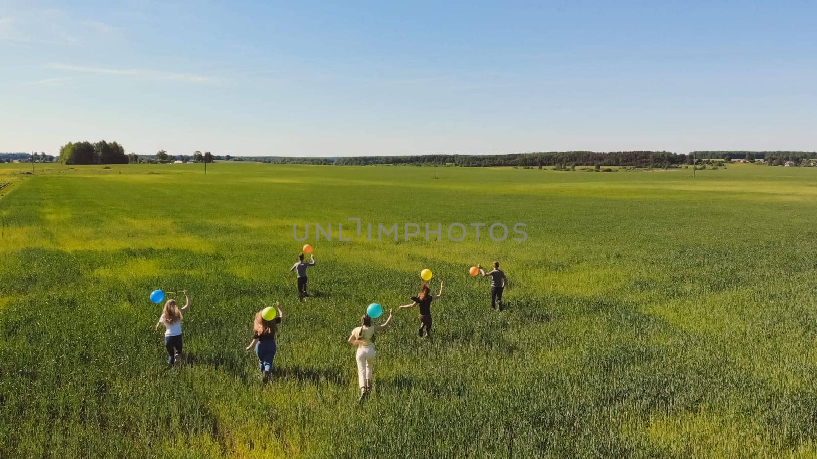 Friends walks across the field with colorful balloons