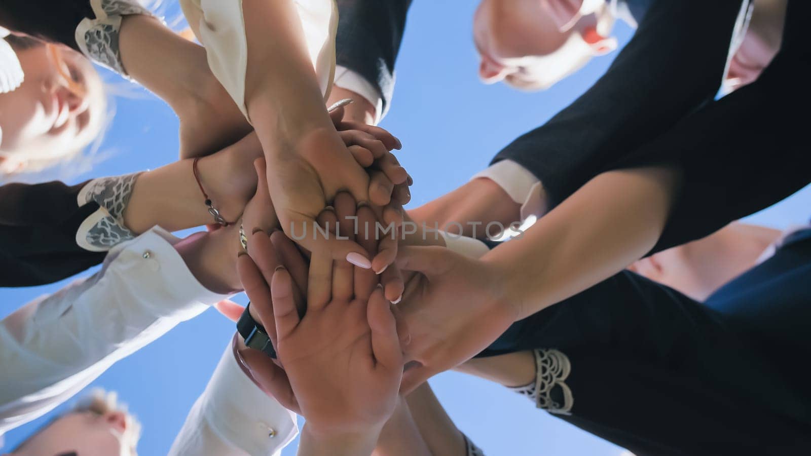 Happy friends graduates join hands together. The concept of a friendly team