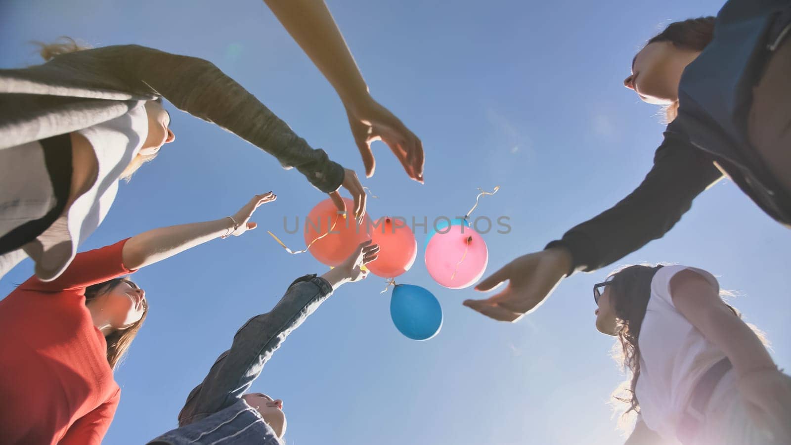 A group of friends release colorful balloons into the sky
