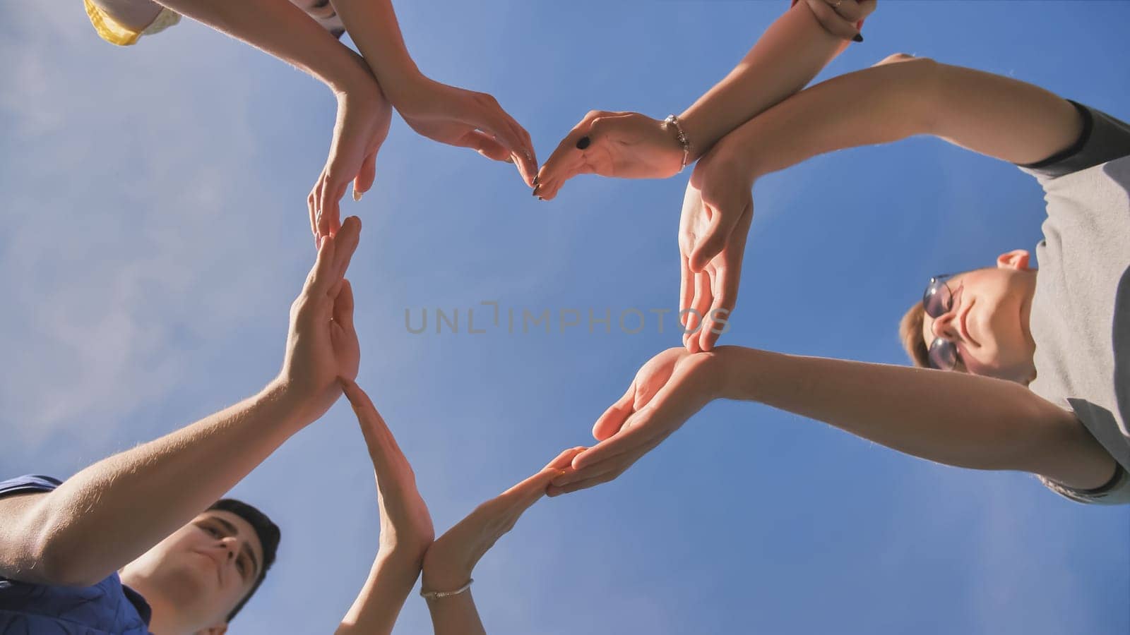 A group of friends makes a heart shape out of their hands