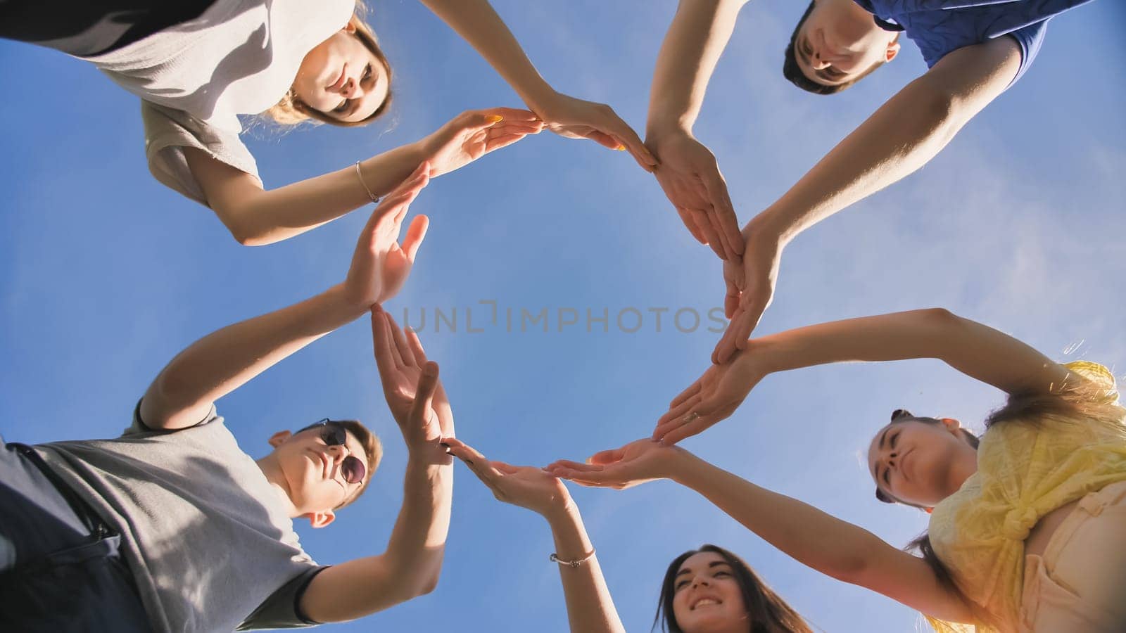 A group of friends makes a circle from the palms of their hands