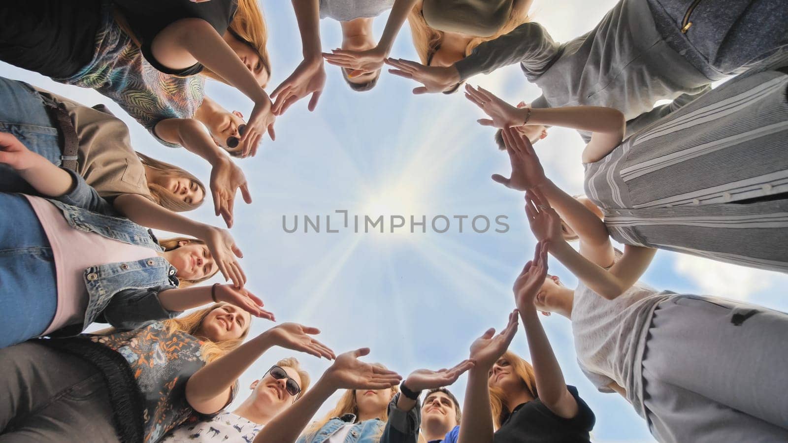 A large group of students makes a circle out of their hands