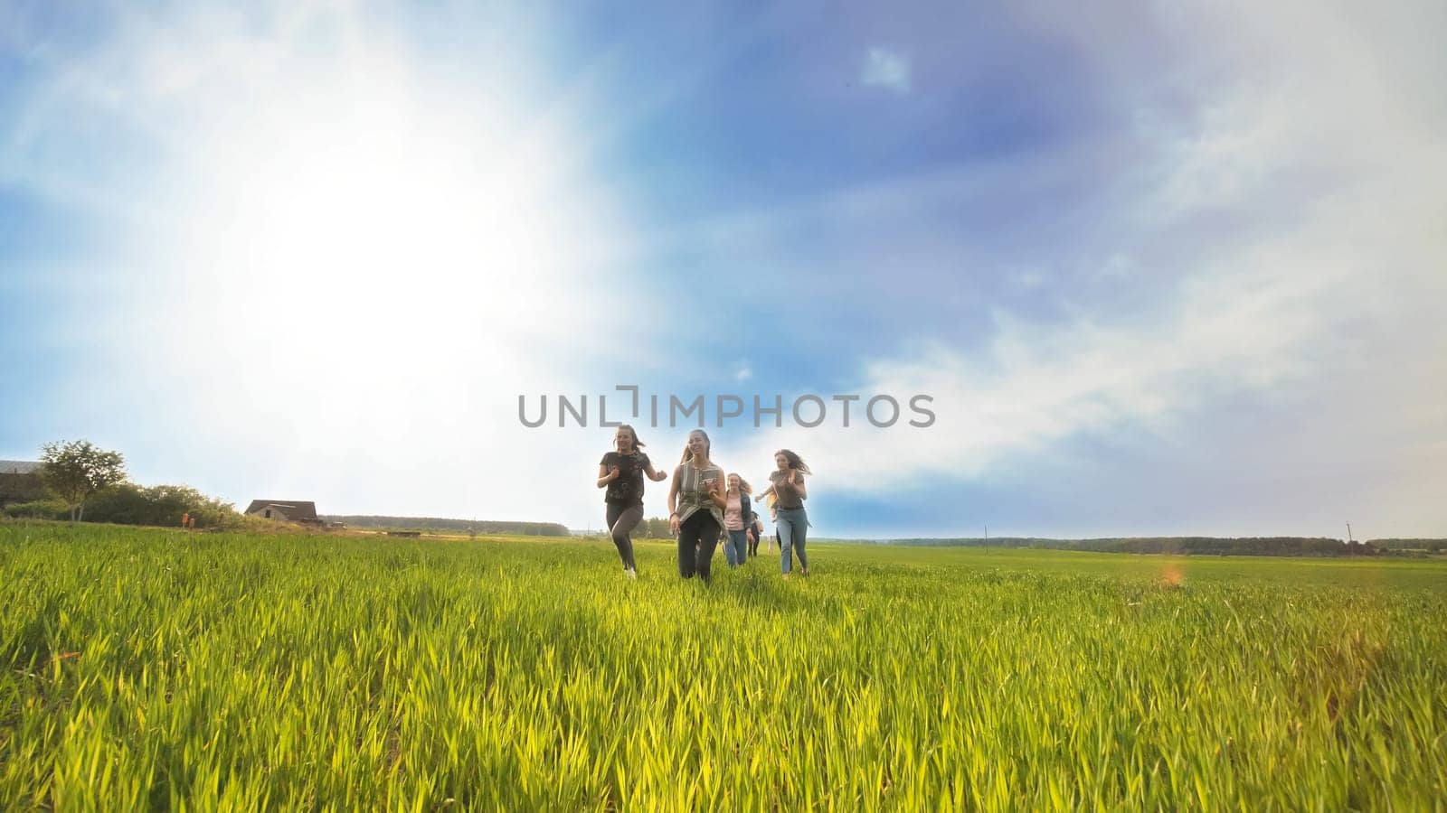 Happy friends run against the backdrop of a beautiful sky and sun