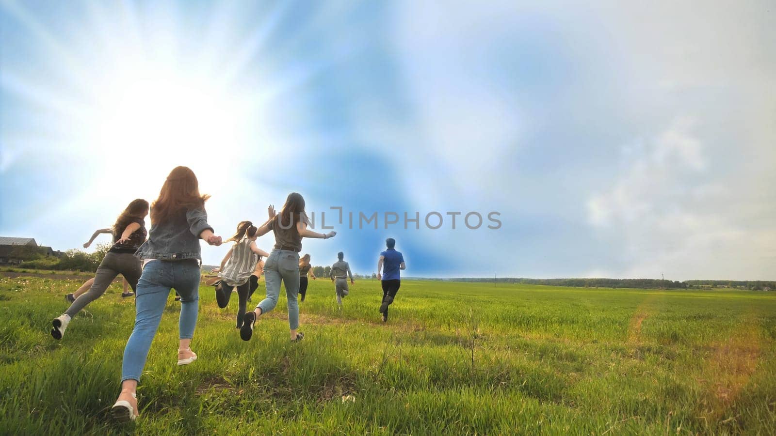 Happy friends run against the backdrop of a beautiful sky and sun