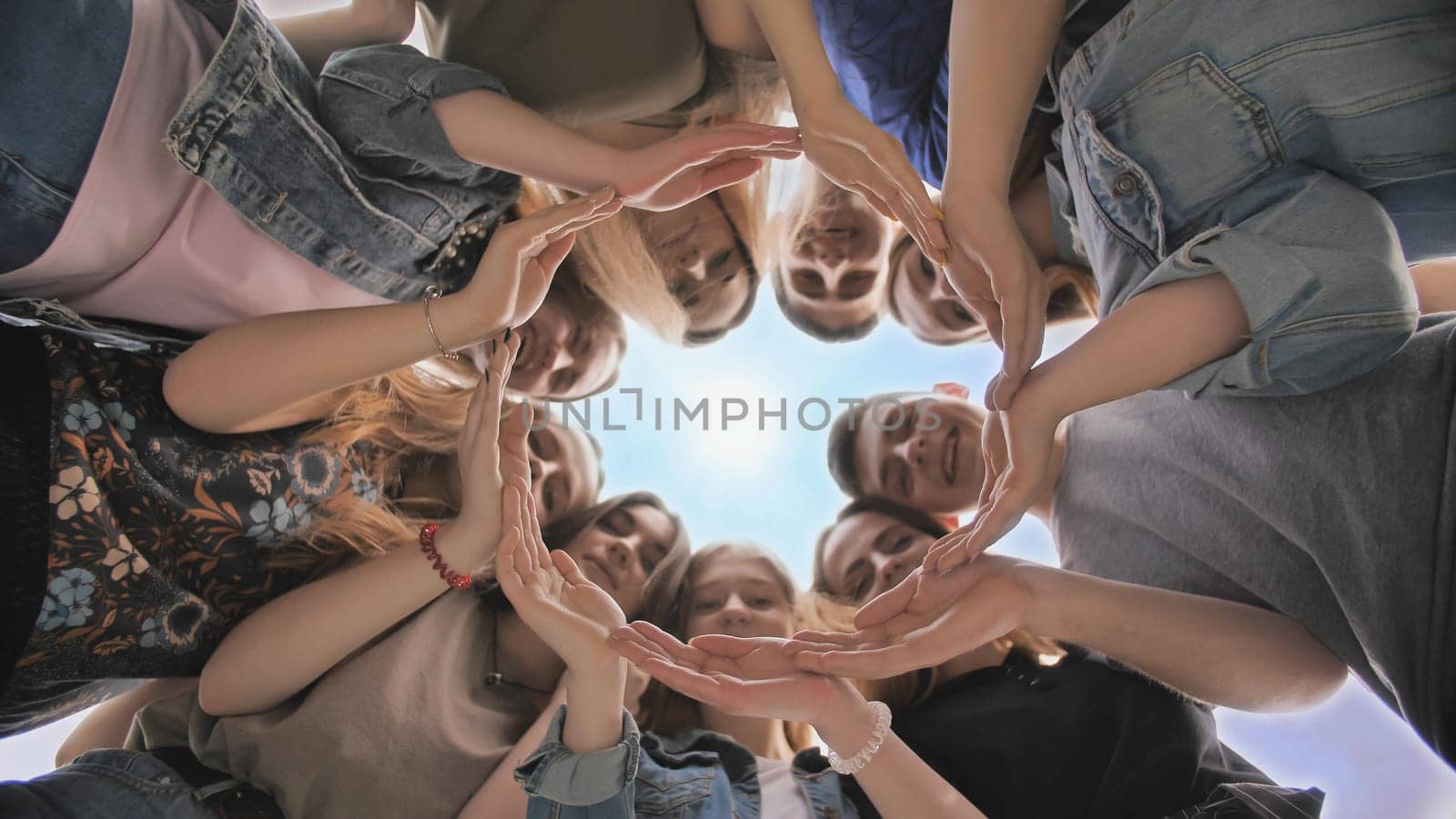 A large group of students makes a circle out of their hands
