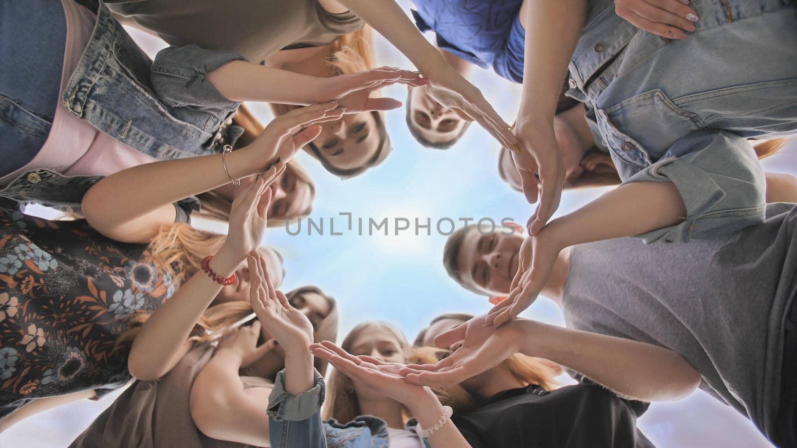 Young people putting their hands in circle on sky background. Unity concept