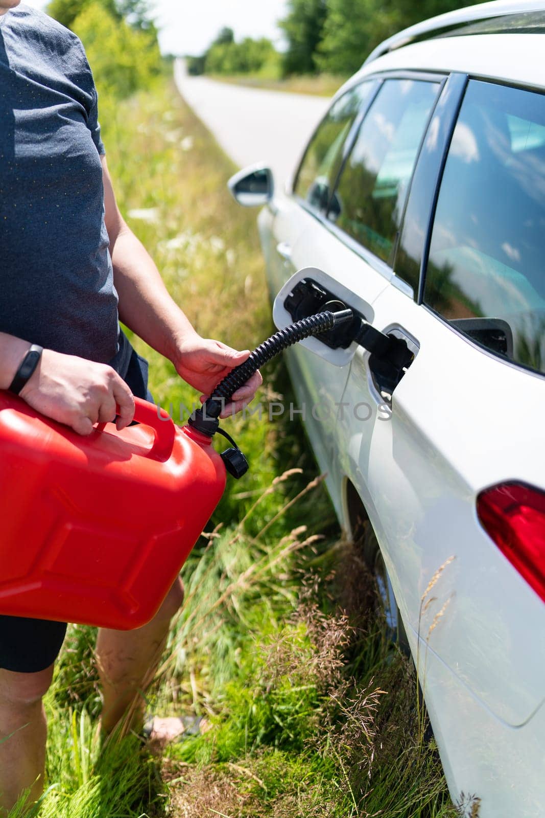 Force majeure, problems on the road, self-refuelling. The driver fills up the empty tank of the car from a red canister on the side of the road