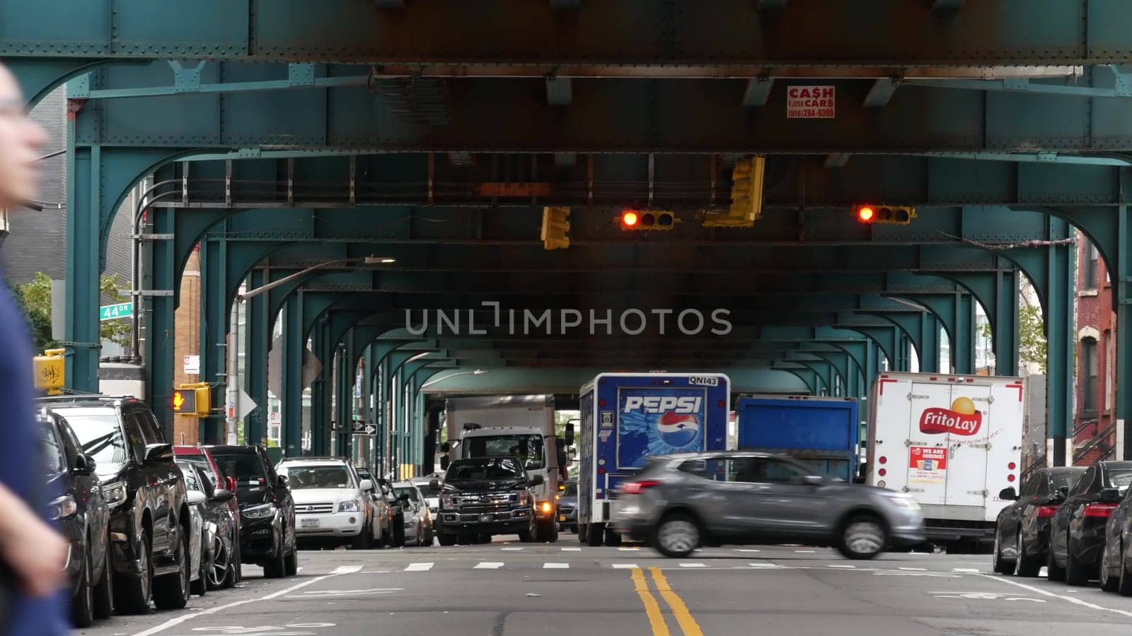 New York City, United States - 31 Aug 2023: Pepsi truck, elevated subway above street. Metropolitan bridge over road, Queens. Long Island metro line. Cars under metallic railway track. NYC urban life.