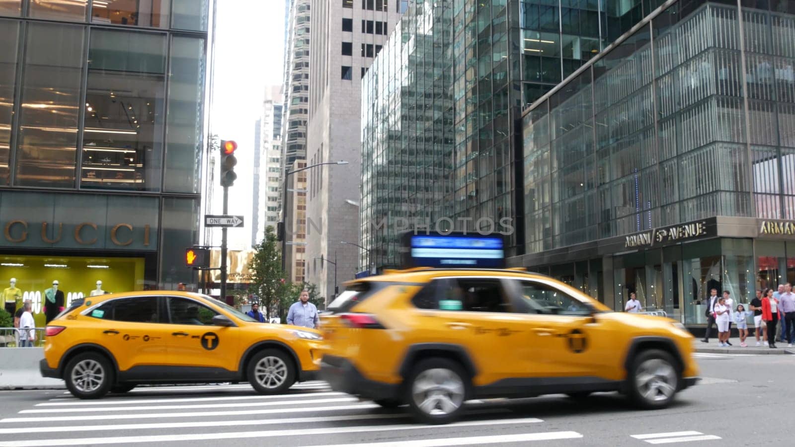 New York City, United States - 13 Sept 2023: Manhattan Midtown street, Fifth 5 avenue. American urban road car traffic. Yellow taxi in USA. People. Boutique fashion stores for shopping, Gucci, Armani.