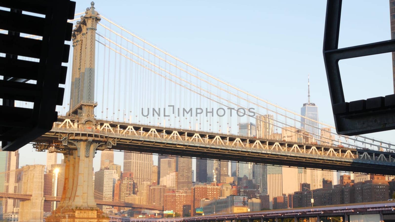 New York City, United States - 7 Sept 2023: Manhattan Bridge to Brooklyn. Pier 35 swings bench, waterfront downtown skyline cityscape. World Trade Center skyscraper, financial district morning sunset.