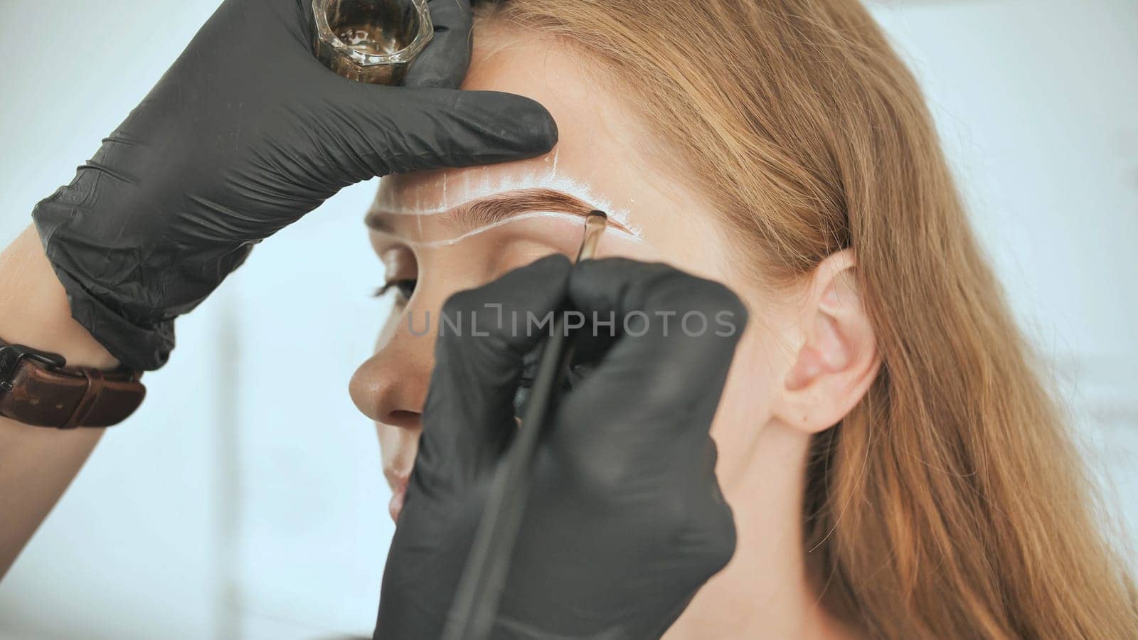 Permanent makeup. Permanent tattooing of eyebrows. Cosmetologist applying permanent make up on eyebrows - eyebrow tattoo