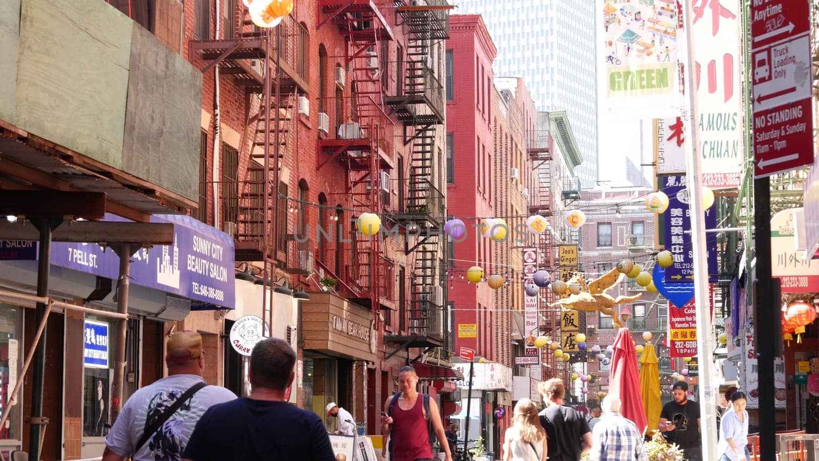 New York City, United States - 14 Sept 2023: Manhattan Chinatown Pell street. Chinese culture, ethnic district architecture, USA. Red brick buildings, round paper lanterns and hieroglyph signs. People