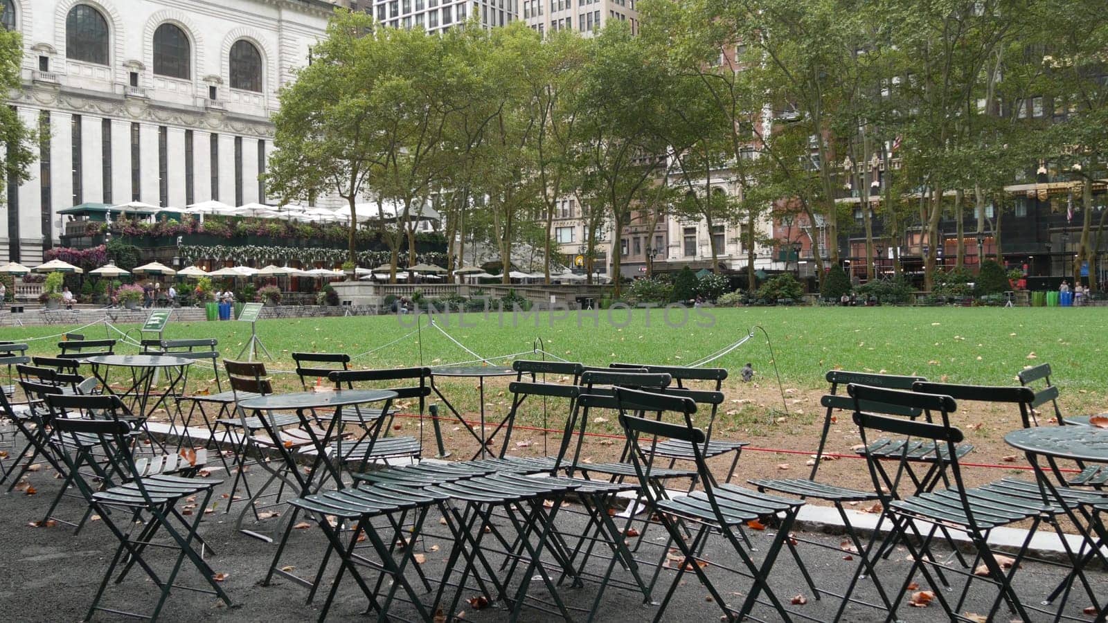 New York City, United States - 13 Sept 2023: Manhattan Midtown Bryant Park with Public library, 42 street and Fifth 5 avenue. USA landmark. Empty chair and table in summer greenery. Green grass lawn.