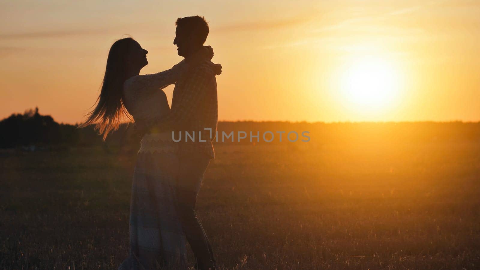 Silhouette of a loving couple hugging on a sunset background