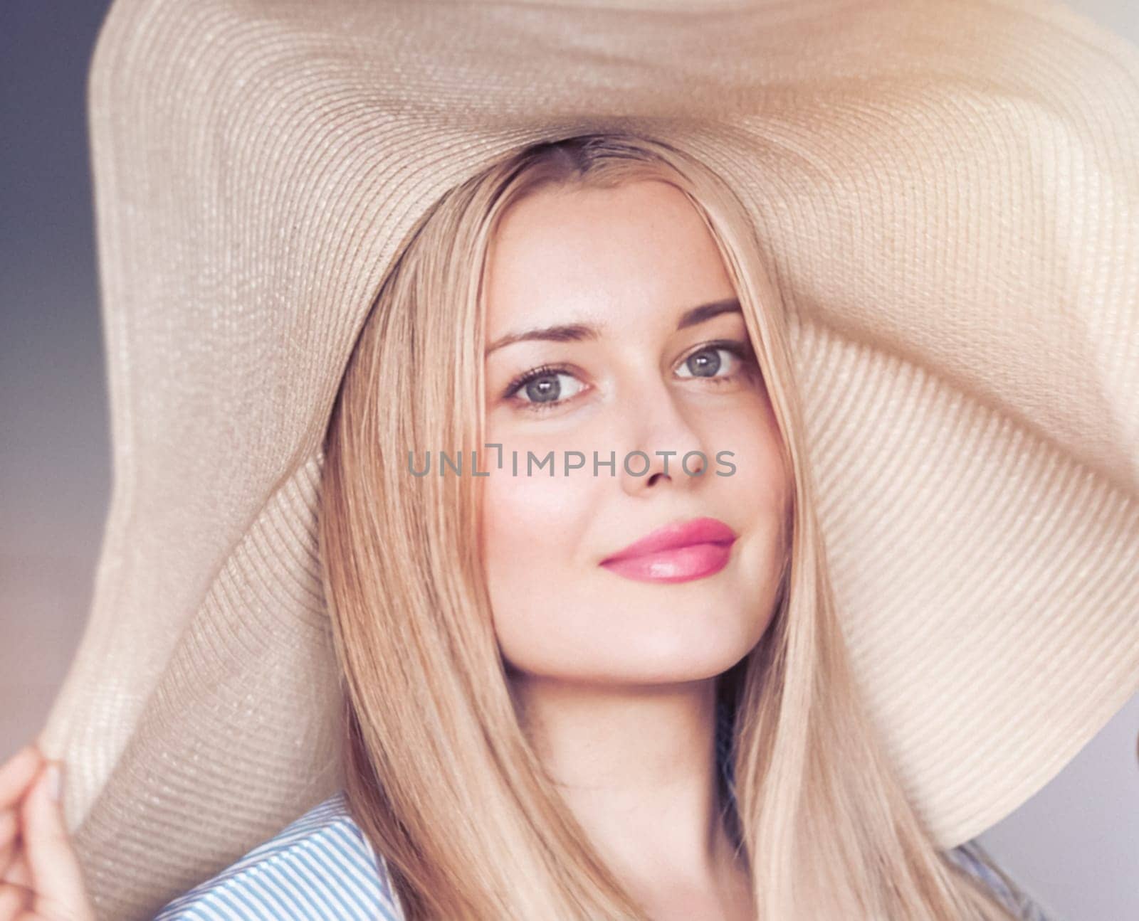 Woman, fashion and summer country charm, blonde beauty and elegance in wide brimmed beach hat. Feminine allure, timeless style and graceful glow. Smile, straw hat and blue striped blouse, natural lighting and effortless charm, fashion look idea