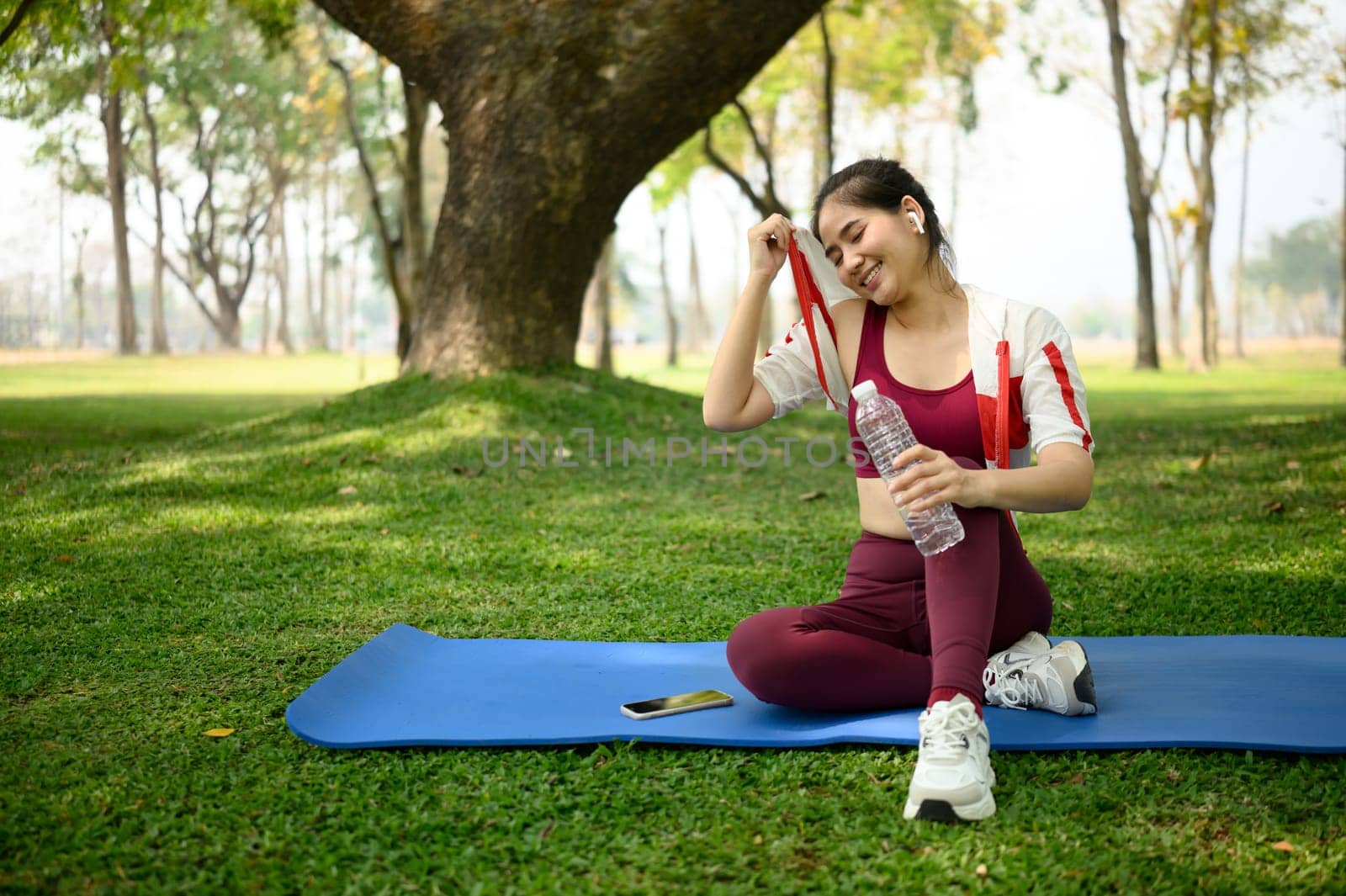 Young woman wiping sweat from her face cooling down after outdoor workout.