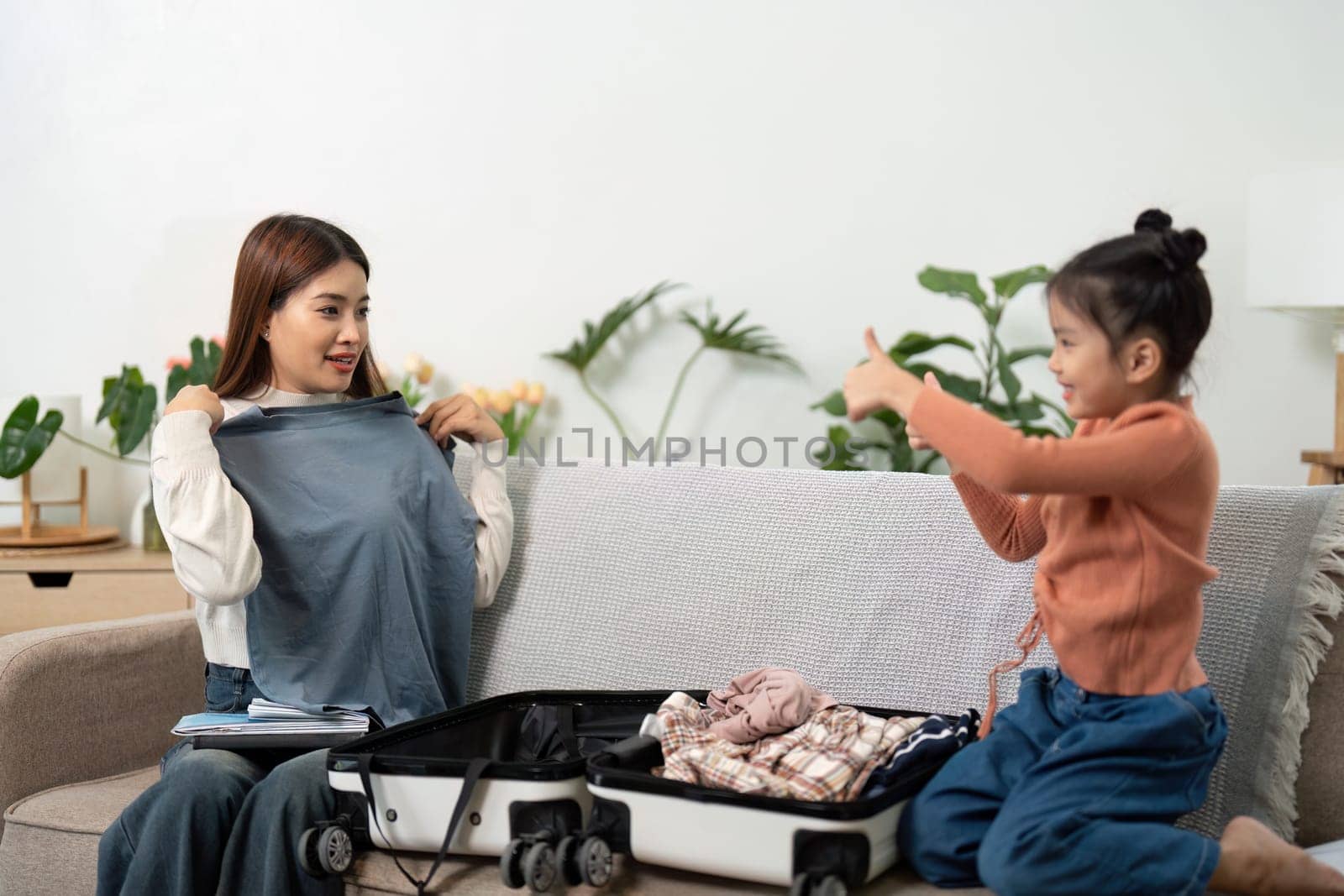 Excited anticipation fills the air as a mother and her daughter pack their suitcase, sharing laughter and making travel plans for an upcoming adventure.