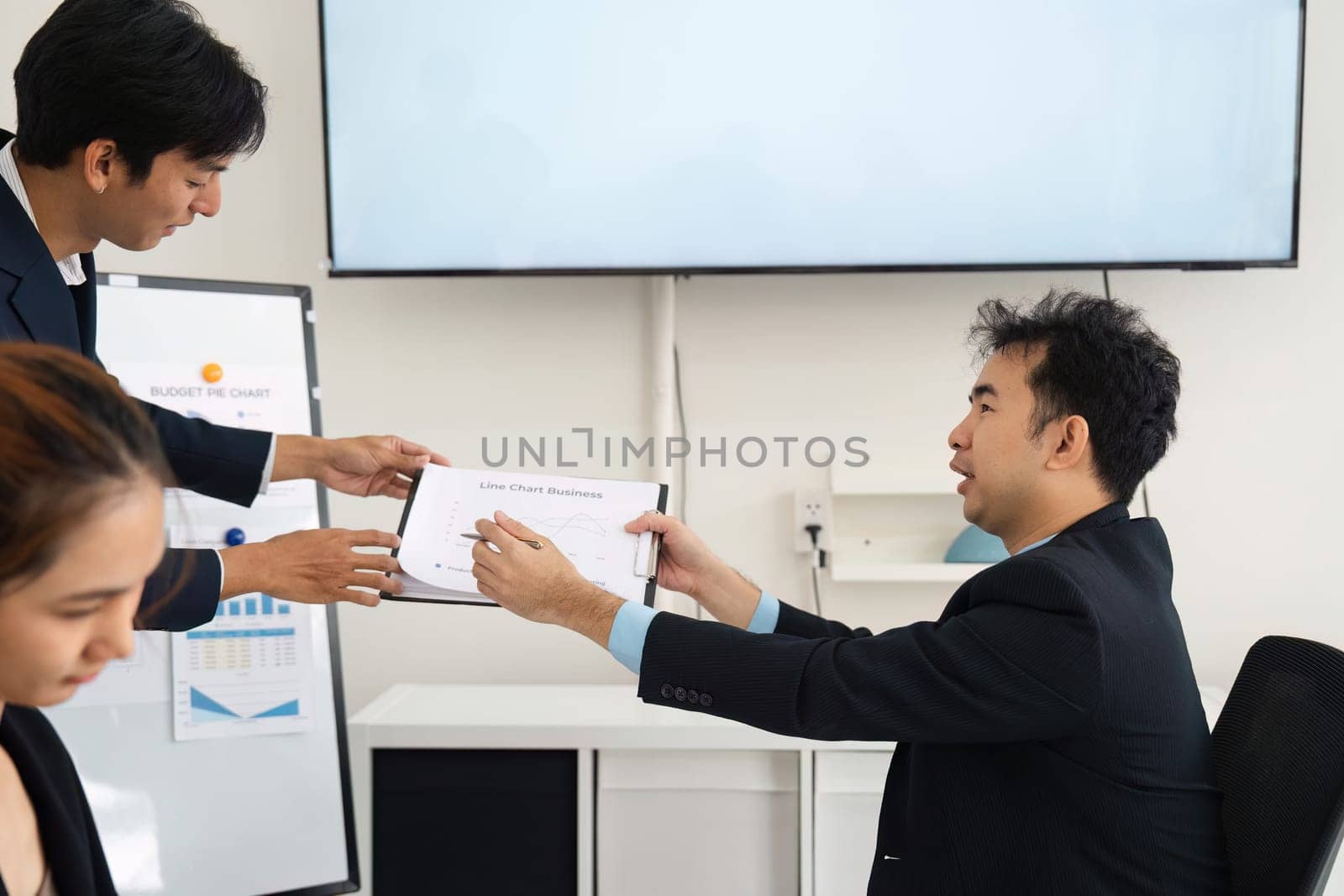 In a strategic meeting, one team member extends a report to a colleague, highlighting team collaboration and hands-on engagement in achieving shared business goals.