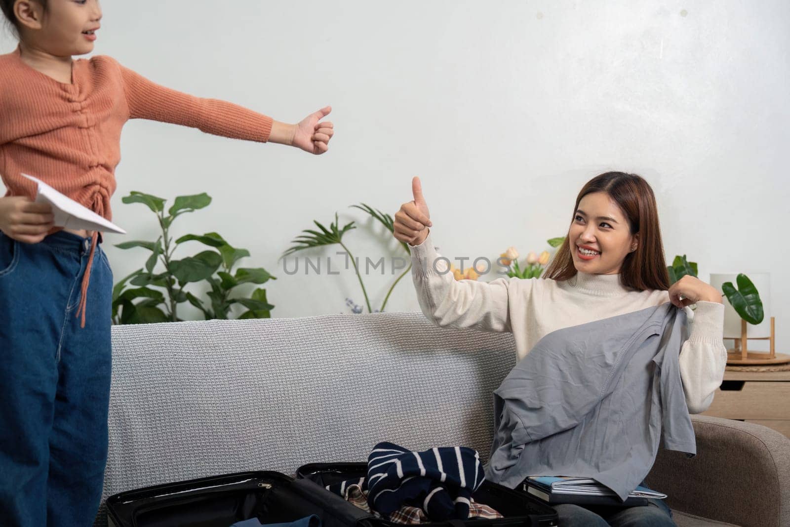 Amidst packing for a trip, the bonding moment intensifies as the girl gives a thumbs up, showcasing her enthusiasm and involvement in the process.