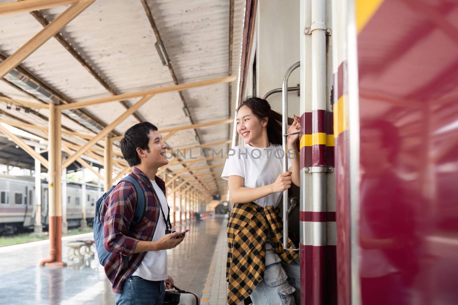 The couple shares a playful moment at the train car, getting ready for their journey. Their smiles reflect the happiness and anticipation of their travel adventure.