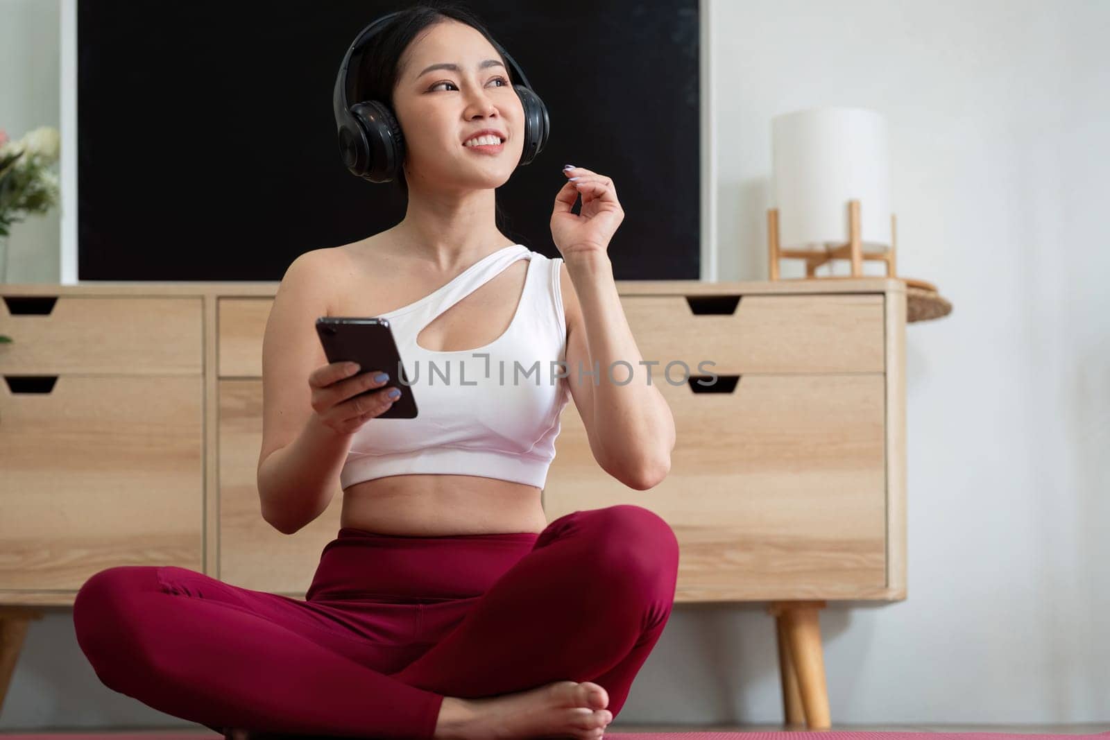 A yogi listens to uplifting music on her headphones during her workout, enhancing her experience and keeping her motivated and focused.