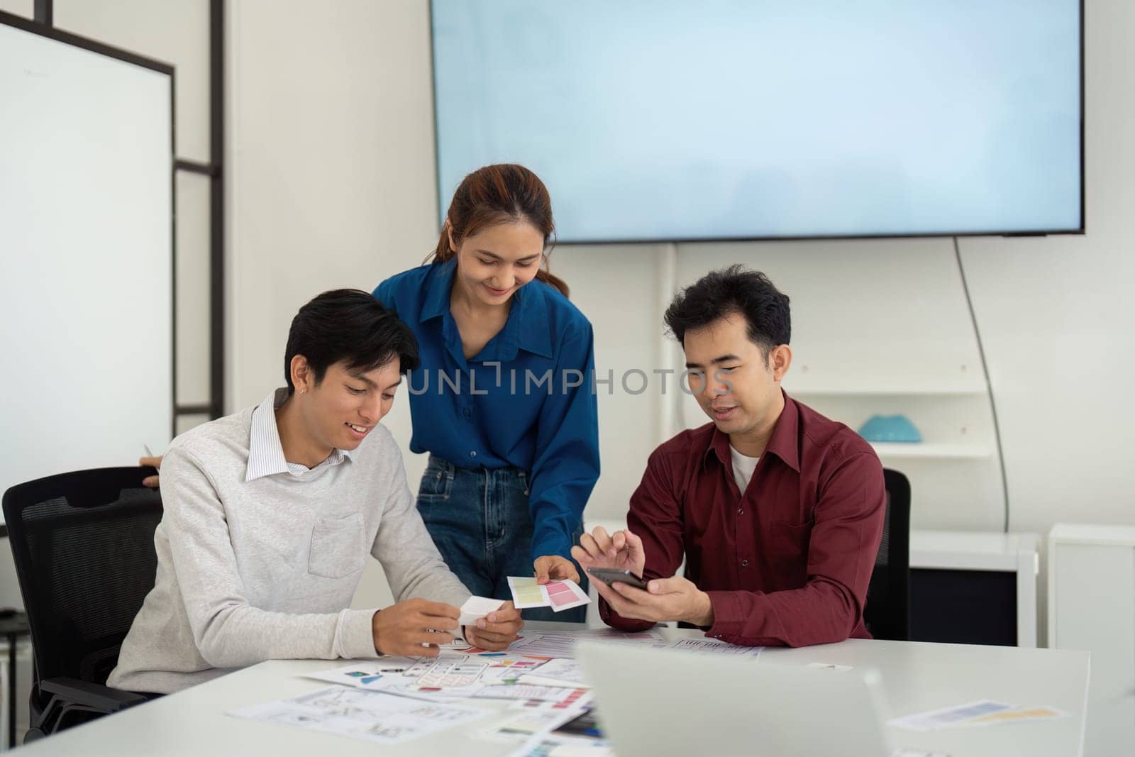 Incollaborative environment, three UX UI designers evaluate design cards and plans, fostering teamwork to refine their projects and enhance functionality.