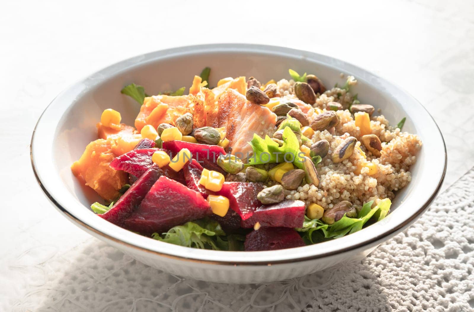 Delicious Quinoa Salmon Poke bowl garnished with Leaves salad, Beetroot, Sweet potato, Sweet corn and Pistachio on Ceramic bowl. use it as your Wallpaper, Poster, Design and Space for text, Selected focus.