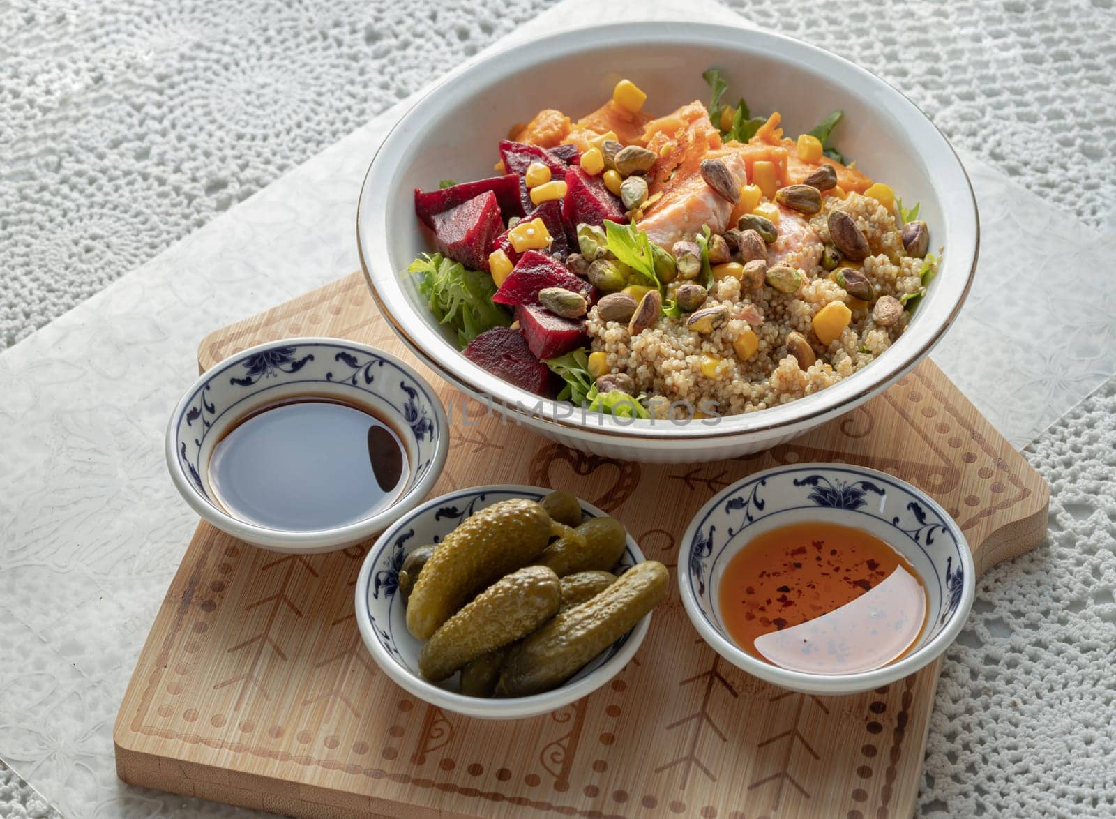 Delicious Quinoa Salmon Poke bowl garnished with Leaves salad, Beetroot, Sweet potato, Sweet corn and Pistachio Served with Pickled Cornichons, Chilli oil and Balsamic vinegar. use it as your Wallpaper, Poster, Design and Space for text, Selected focus.