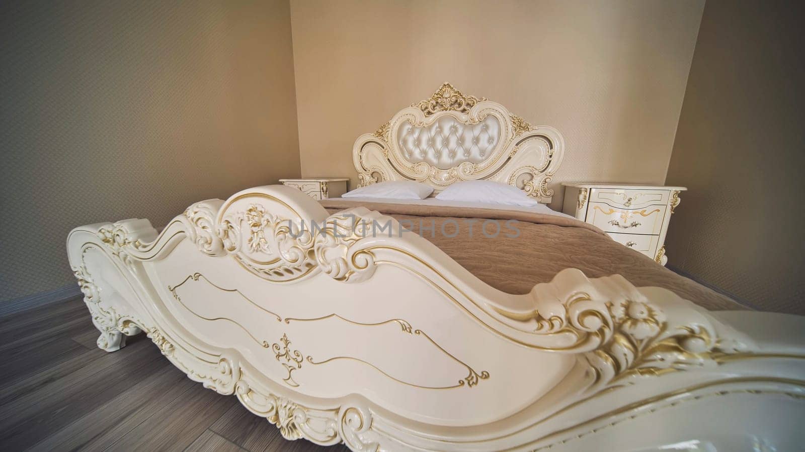 Luxurious hotel bedroom featuring ornate king size bed with intricate wooden headboard, conveying sophisticated romantic atmosphere