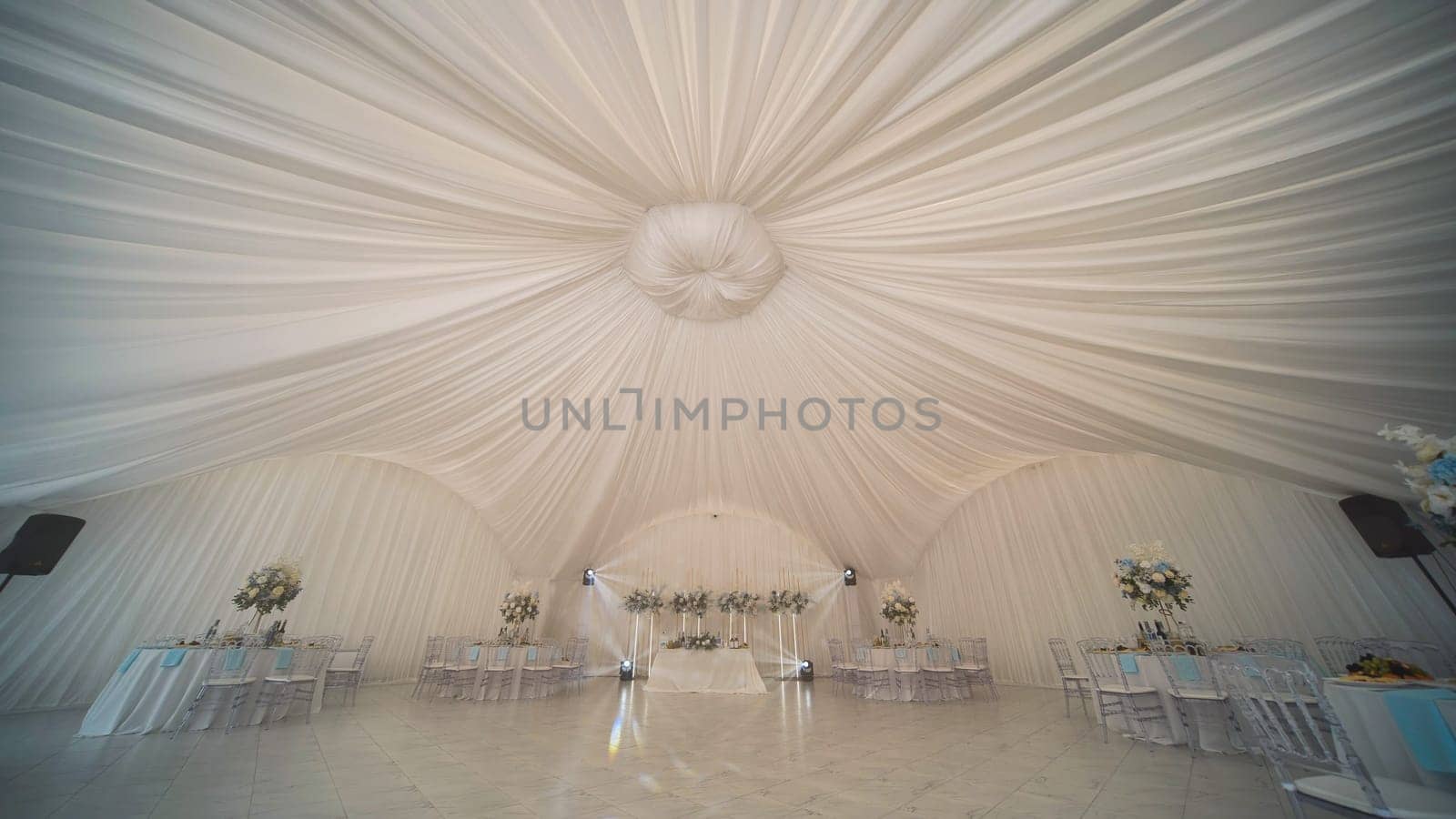 Elegant wedding venue decorated with flowing white fabrics and flower arrangements, creating a romantic atmosphere for celebrating marriage
