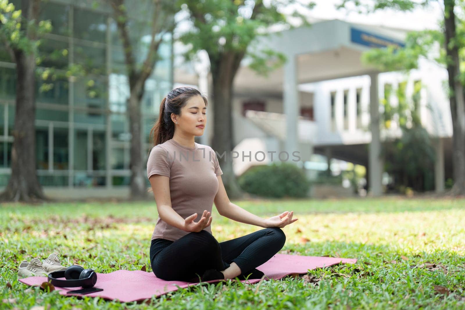 A serene moment as a woman sits cross-legged on a mat, engaging in meditation amidst nature to enhance her mental clarity and inner peace.