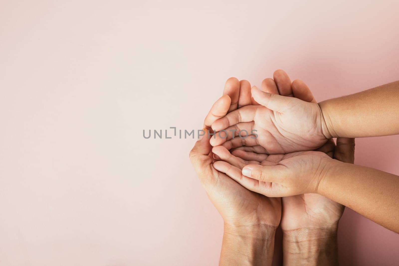 Top view of parents and kid holding empty hands together on a color background. Family day celebrating togetherness and support.