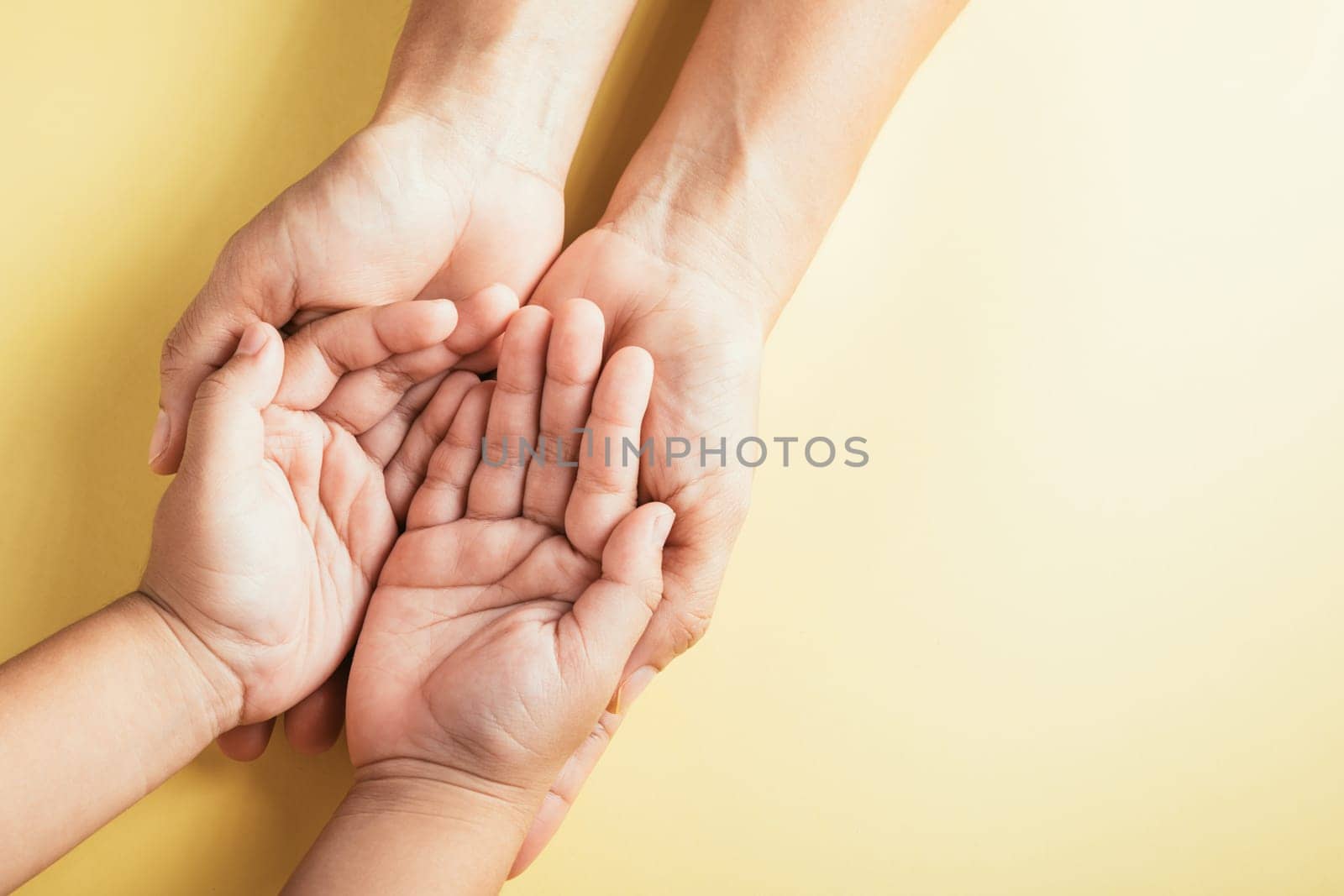 Close-up top view of family hands stacked on an isolated background in a studio shot. Parents and kids hold an empty space portraying support and love for Family and Parents Day.