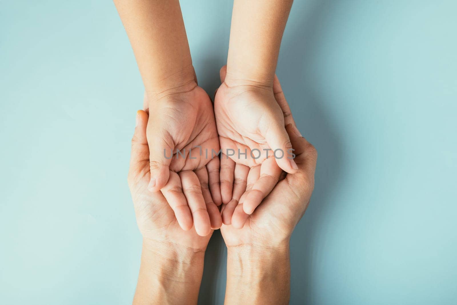 Top view studio shot of family hands stacked isolated background. Parents and kid hold empty space symbolizing support on Family and Parents Day.