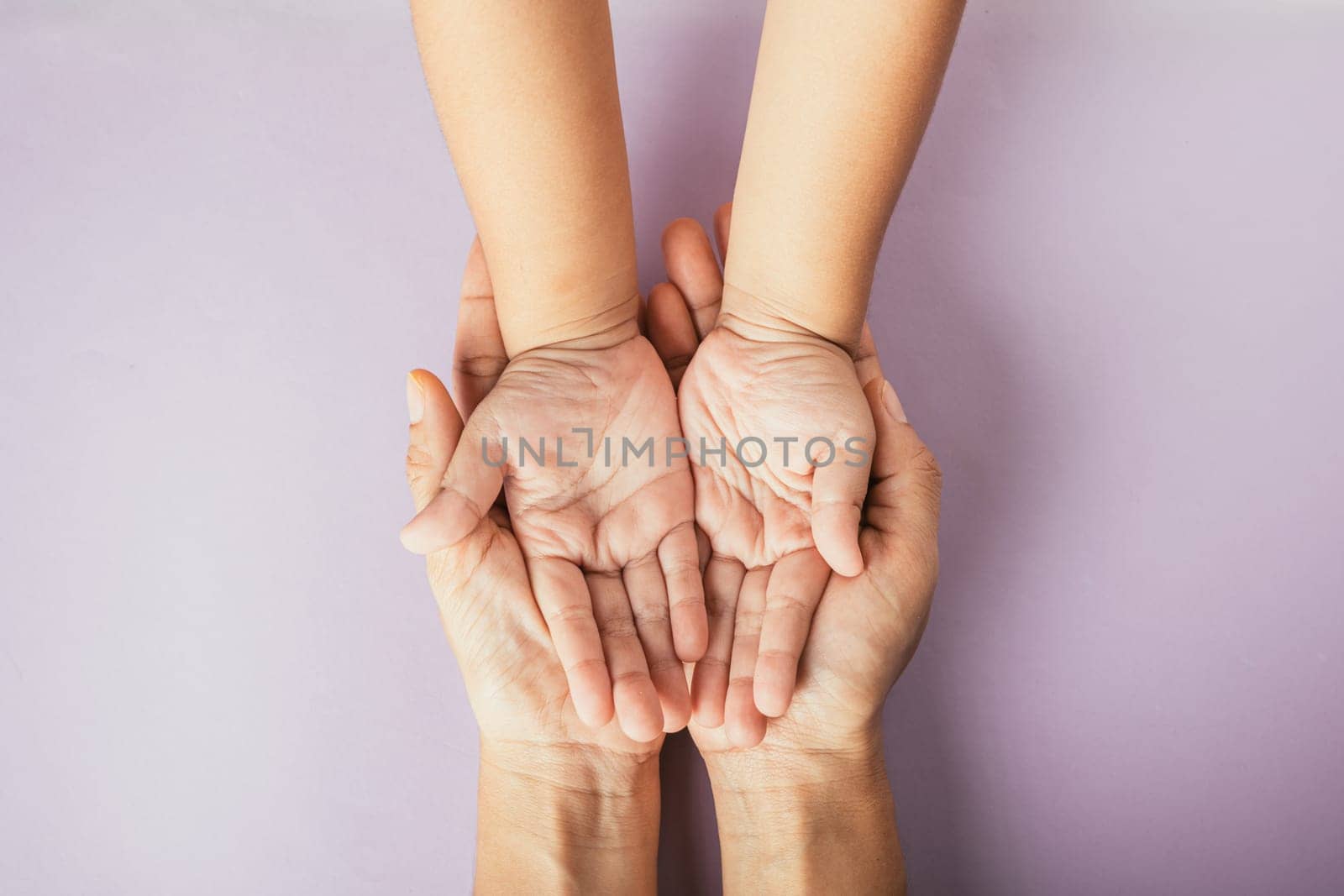 Celebrating family day, Top view of parents and kid holding empty hands together on a color background. Space for text.