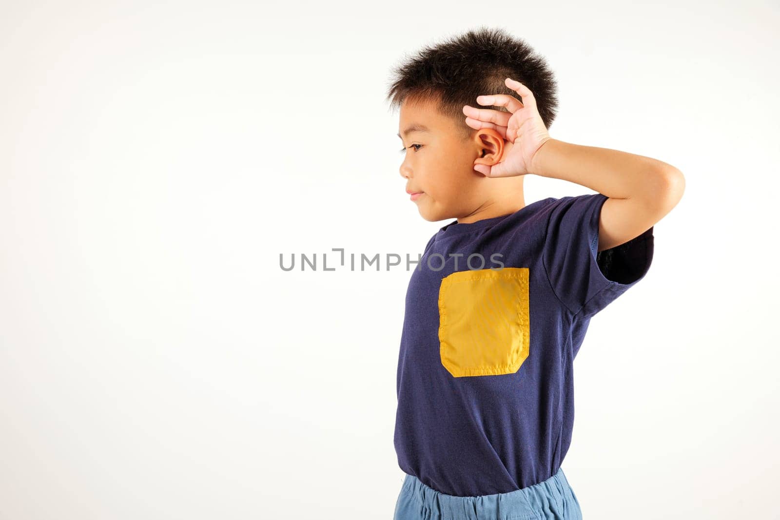 Portrait Asian young child smiling overhearing listening sound to gossip with attention with hand on ear studio shot isolated on white background with copy space hearing gesture, primary kid boy