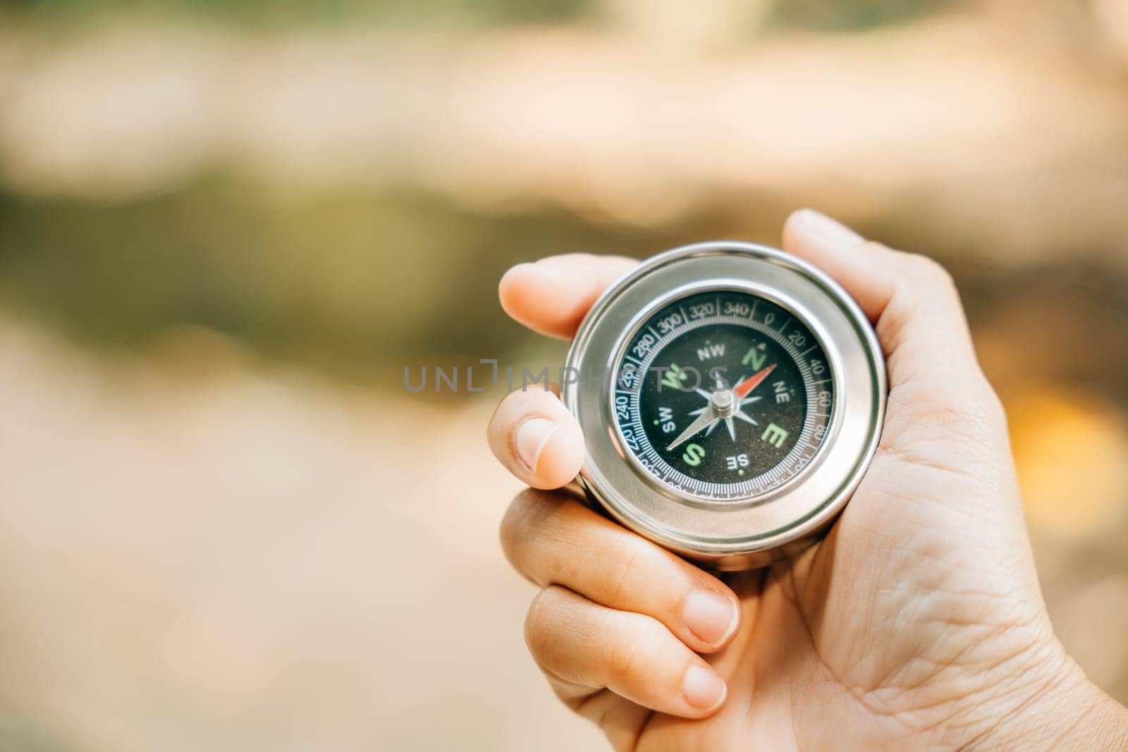 Traveler holds a compass in a park finding her way amidst confusion. The compass in her hand symbolizes guidance exploration and the journey to conquer defeat.