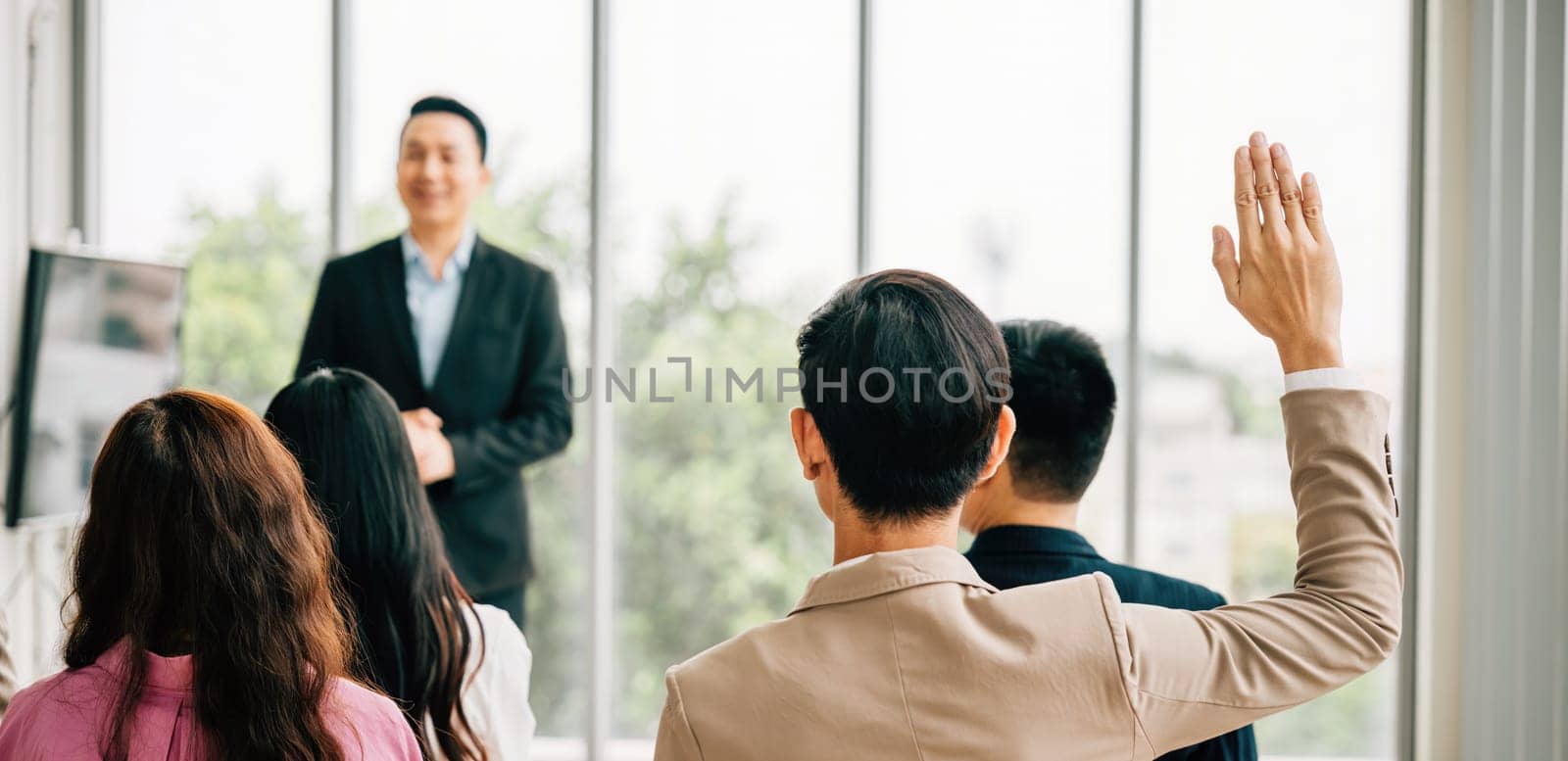 A group of professionals in a seminar meeting room raises their hands to ask questions, symbolizing an engaged audience ready to interact and learn. It's all about the concept of active participation.
