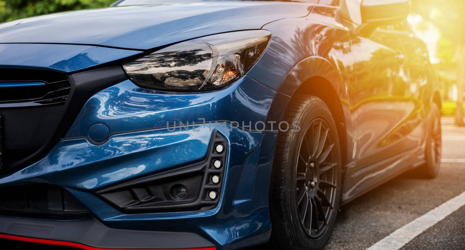 Luxury blue car's modern xenon headlight lamp. Shiny chrome design safety technology for night driving. Clean reflective sedan headlight in car industry. Detail on one of the LED car headlights