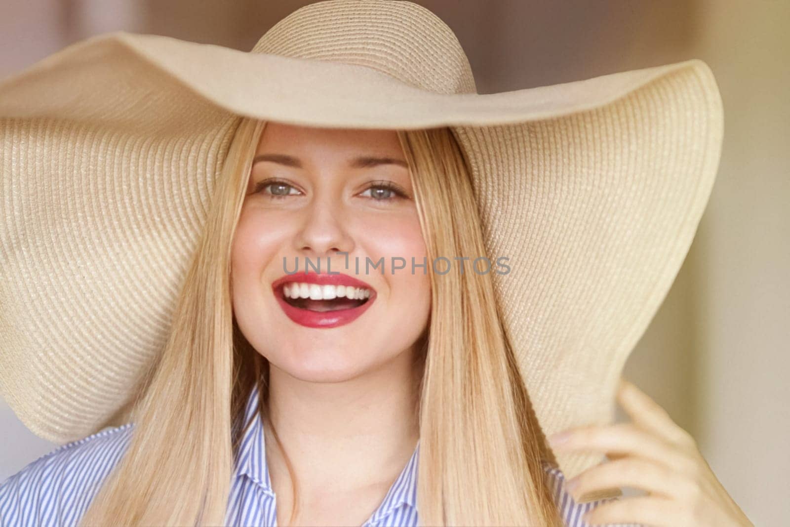 Woman, fashion and summer country charm, blonde beauty and elegance in wide brimmed beach hat. Feminine allure, timeless style and graceful glow. Smile, straw hat and blue striped blouse, natural lighting and effortless charm, fashion look idea