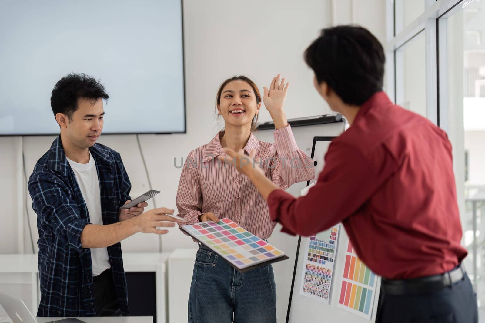 A moment of joy arises as the team celebrates their creative process, exchanging ideas and showcasing design elements in an uplifting atmosphere.