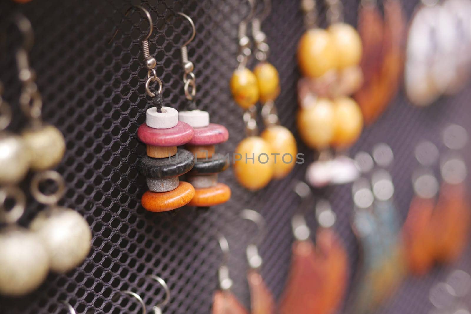 Various handmade earrings with vibrant colors are on display for sale.