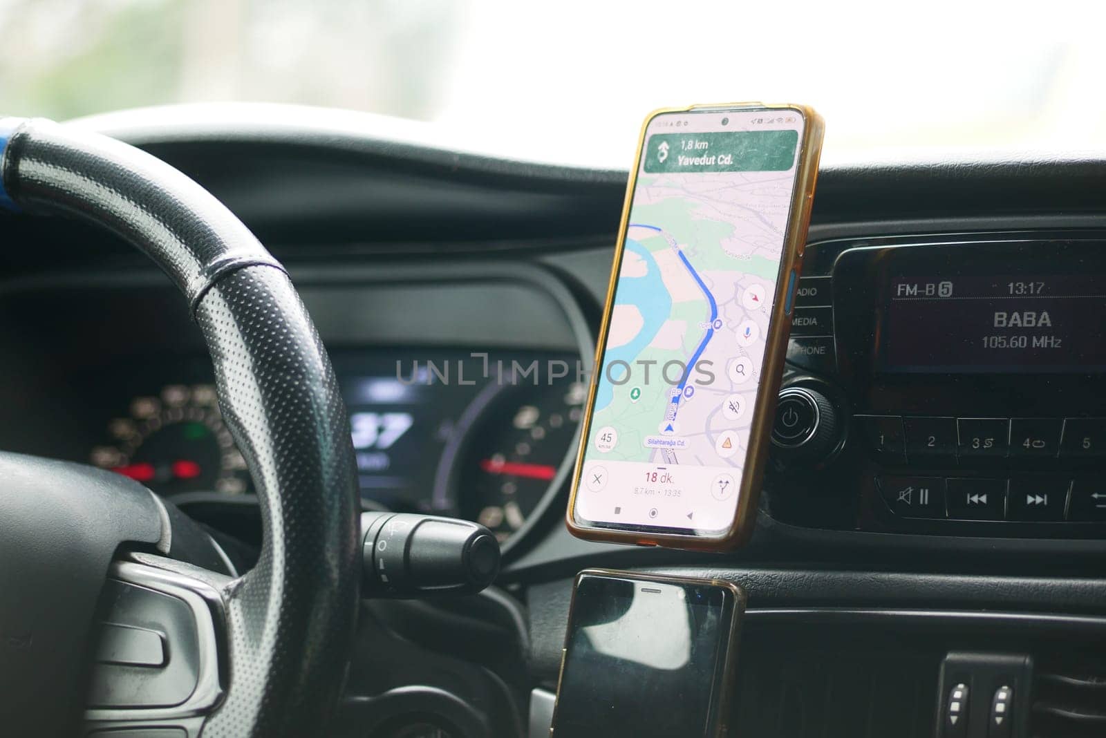 A smartphone mounted in a vehicle shows directions on a winding road.